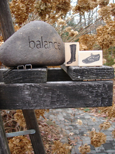 1997 New Rubber Stamps City Slicker Theme One Size: Two wooden rubber stamps on a bench, featuring a knee boot and a saddle shoe design, alongside a rock with an engraved word.