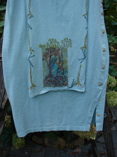 1994 Apron Skirt Magic Garden Menthe Size 1 features a painted tree design on a blue shirt, showcasing a vintage style with a unique layered look and curved side buttons.
