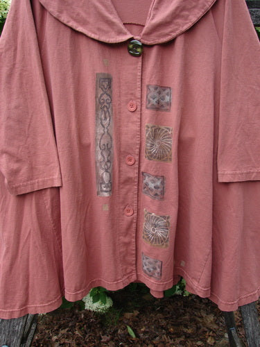 Bluefishfinder.com 1994 Wanderer's Jacket Continuous Garden Monrovian Brick Size 2 in muted brick pink, with a wide rounded collar, oversized sleeves, and a front button placket. The soft, worn fabric is marked by a vertical ornamental panel and a row of square patch motifs.