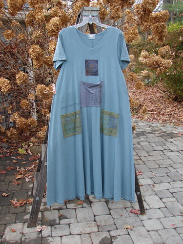 2000 PMU City Side Dress Directional Puddle Size 1 on a clothes rack with patchwork designs, featuring three front painted pockets, a V-shaped neckline, and a unique rear center patch.