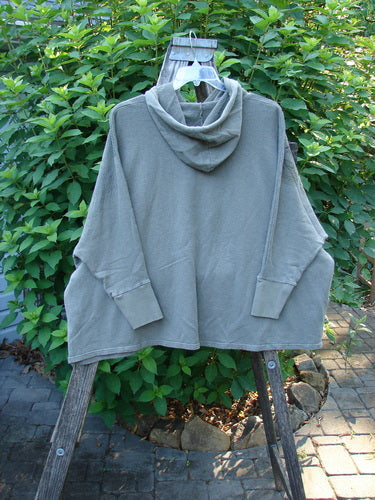 Barclay NWT Cotton Hemp Hooded Folklore Pullover Blossom Grey Lolite OSFA displayed on a wooden rack, showcasing its cordless hood, ribbed cuffs, and dual drop pockets with a wide square flared swing design.