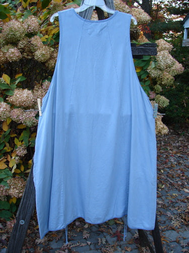 Barclay NWT Twill Joyous Jumper Unpainted Sky Size 2, displayed hanging on a clothesline, showcasing its slightly shallow neckline, widening vertical seams, and double drop front exterior pockets.