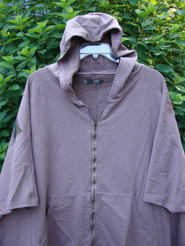 Barclay Hooded Postcard Zipper Jacket in Vintage Rose features a cozy hood, full zipper front, and dolman shoulders, displayed on a hanger, highlighting its unique Roman wings design on the back.