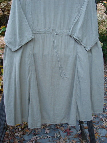 Barclay NWT Batiste Bliss Dress Fallen Petal Dovetail Size 2 displayed on a wooden rack, showcasing short sleeves, a soft rounded neckline, and two exterior pockets.