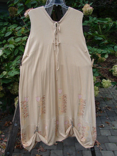 Barclay Salt Water Taffy Jumper Tulip Garden Wheat Size 2 is displayed on a clothesline, showcasing its pink floral pattern, tie-on pockets, and shell-textured buttons, embodying vintage Blue Fish Clothing style.