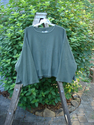 Barclay Patched Thermal Donna Top Out West Deep Army OSFA displayed on a wooden ladder, featuring a waffle texture, wide neckline, belled sleeves, and rear patch detailing.