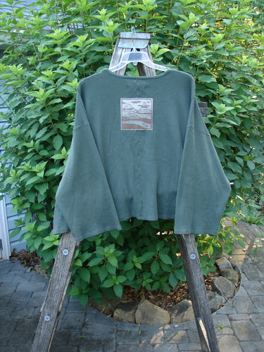 Barclay Patched Thermal Donna Top Out West Deep Army OSFA displayed on a swinger; features bell sleeves, drop shoulders, waffle texture, and a rear patch, highlighting unique design details.