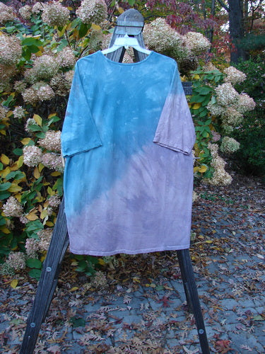 Barclay NWT Tournesol Top Abstract Floral Denim Amethyst OSFA displayed on an outdoor swing, showcasing its tunic length, loose three-quarter sleeves, and varying hemline against a natural backdrop.