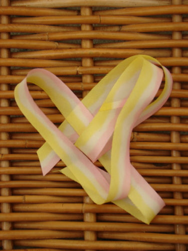 Blue Fish Hand Dyed Silk Ribbon in Sun Mist Morning 108 x 5/8th, displayed on a wicker surface, showcasing its light, flowing texture and unique hand-dipped color variance.