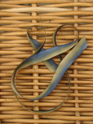 Blue Fish Hand Dyed Silk Ribbon in Rock Moss 108 x 5/8th, displayed on a woven surface, freshly cut on the bias, showcasing its light, flowing texture and unique color variations.