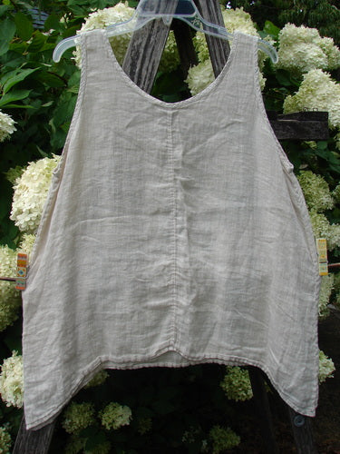 Barclay Linen Altoll Top Blossom Reach Creme Size 0, a sleeveless cream linen top with a soft crinkled texture, scoop neckline, and gently flared hem, hanging from a clear hanger against leafy white hydrangeas.