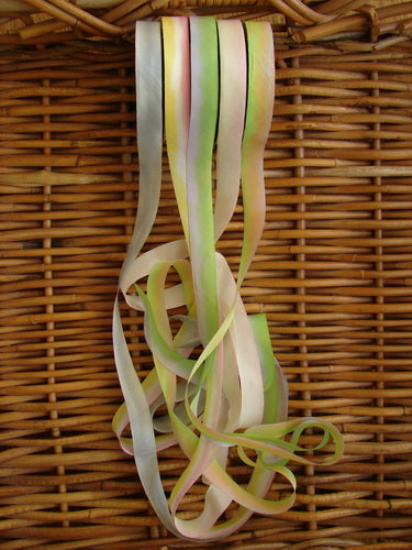 Blue Fish Hand Dyed Silk Ribbon in Melba Sun, 108 x 5/8th, displayed on a wicker surface, showcasing its light, flowing texture and unique color variance.