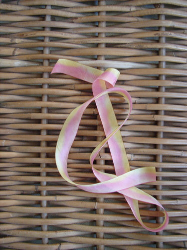 Blue Fish Hand Dyed Silk Ribbon in Melba Sun 108 x 5/8th displayed on a woven mat, highlighting its light and flowing texture, perfect for vintage Blue Fish clothing adornments.