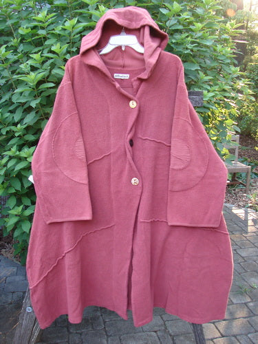 Barclay Celtic Moss Hooded Curve Coat in Unpainted Sunset, featuring a cozy hood, S-shaped button line, giant circle sleeve patches, and a sweeping A-line flair with deep pockets.