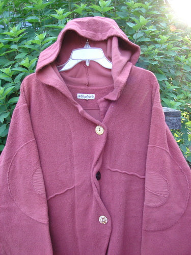 Barclay Celtic Moss Hooded Curve Coat Unpainted Sunset Size 2. Showcases a textured, dense feel with a sweeping A-line flair, deep pockets, and an S-shaped button line. Features giant circle sleeve patches.