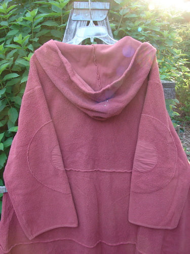 Barclay Celtic Moss Hooded Curve Coat Unpainted Sunset Size 2 displayed on a plastic swinger, highlighting its cozy hood, circle sleeve patches, S-shaped button line, and sweeping A-line flair.