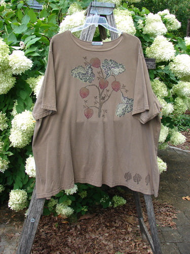 Barclay Short Sleeved Studio Tee Tree Offer Fauna Size 3 in muted taupe, a short-sleeved tee with a relaxed drape and faded botanical print centered on the chest. The lightweight knit hangs from a hanger outdoors, framed by dense green foliage and white hydrangea blooms.