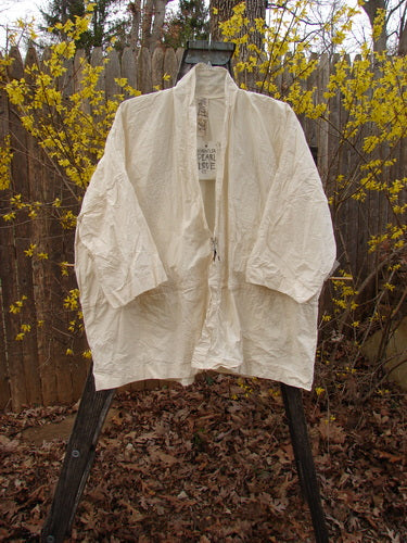 Magnolia Pearl NWT Cotton Poplin Wabi Kimono Natural OSFA displayed outdoors on a swinger, featuring an open front with sectional panels and a square boxy shape, embodying simplicity and versatility.