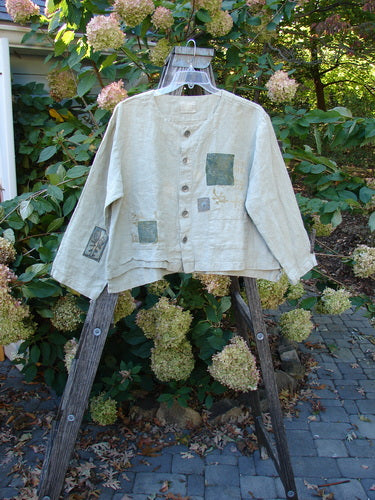 1999 PMU Patched Summercloth Hemp Crop Jacket features a boxy, vented crop design with metal buttons, drop shoulders, and nature-inspired paint on a wooden stand.