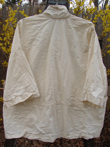 Magnolia Pearl NWT Cotton Poplin Wabi Kimono Natural OSFA displayed on a clothes rack outdoors, highlighting its open front and boxy shape, embodying understated elegance suitable for pairing with other pieces.