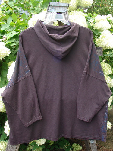 Barclay Cotton Lycra Dolman Roo Pocket Hoodie in Pansy Rose Deep Bark, an oversized dark brown pullover with a draped hood, wide dolman sleeves, and a roomy front pocket. The soft cotton-lycra knit hangs loosely on a hanger, with subtle blue speckling along the sleeves.