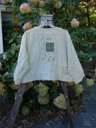 1999 PMU Patched Summercloth Hemp Crop Jacket features a boxy crop design with metal buttons and nature-inspired paint, displayed on a wooden rack, highlighting its unique vintage craftsmanship from Bluefishfinder.com.