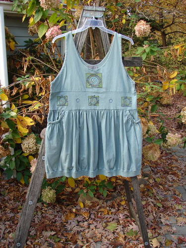 1996 Amusement Jumper Round Wind Trinket Size 1 on a wooden ladder, showcasing its unique double-layered bodice, drawcord back, and rounded wind theme pattern, emphasizing its vintage charm and versatility.