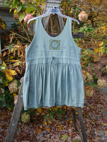 1996 Amusement Jumper Round Wind Trinket Size 1 displayed on a wooden ladder, showcasing its double-layered bodice, nifty draw cord back, and detailed rounded wind theme design, emphasizing its vintage charm.