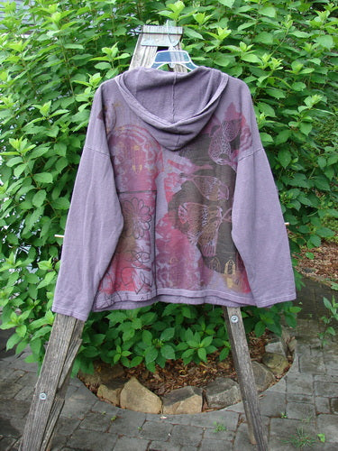 Barclay Cotton Hemp Roo Pocket Hoodie Pullover Rear Birdie Plum OSFA displayed on a wooden rack, showcasing a cozy fleece texture with a kangaroo pocket and distinctive shoulder and sleeve design.