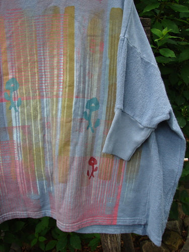 Barclay Hemp Cotton Banded Sleeve Colors Sweatshirt Grid Flower Peacock OSFA displayed outdoors, showcasing its wide boxy shape, rounded neckline, dolman sleeves, floral grid pattern, and banded hemline.