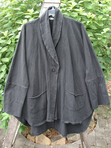 Barclay Reprocessed Golden Hour Deco Jacket Unpainted Black OSFA showcased on a rack, highlighting its heavy-weight organic cotton material, single button closure, drop dolman shoulders, and oversized raw-edged pockets.