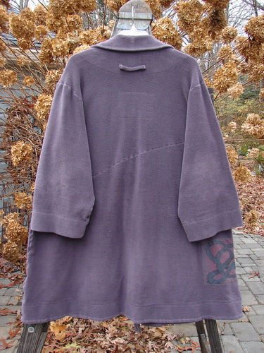 2000 Patched Celtic Moss Highlander Coat in Aubergine, Size 0, displayed on a hanger, showcasing its unique horizontal seams, empire waistline, and three front buttons, with a plush, dense fleece fabric.