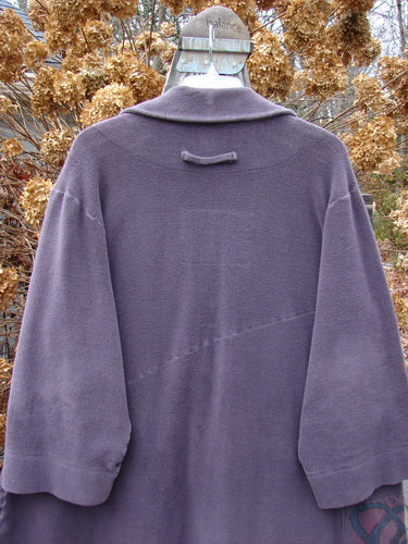2000 Patched Celtic Moss Highlander Coat in Aubergine Size 0 displayed on a hanger, showcasing its unique seams, large collar, and front pocket with Blue Fish signature patches.
