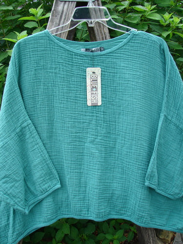 Barclay NWT Gauze Square Mariposa Pullover Unpainted Jade OSFA displayed on a clothes rack, showcasing its wide three-quarter length sleeves and boxy flowy shape in lightweight textured cotton gauze.