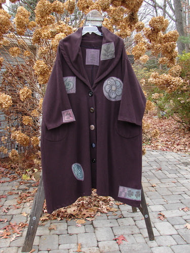 1994 Patched Wool Falling Snow Coat Plum Wine OSFA displayed on a rack, featuring floral patches, four vintage buttons, deep side pockets, and a large shawl collar.