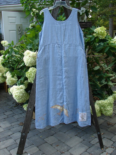1999 Handkerchief Linen Sunbeam Dress Love Dove Water Altered Size 1 displayed on a wooden rack, showcasing its full flared lower and downward curved empire waist seam.