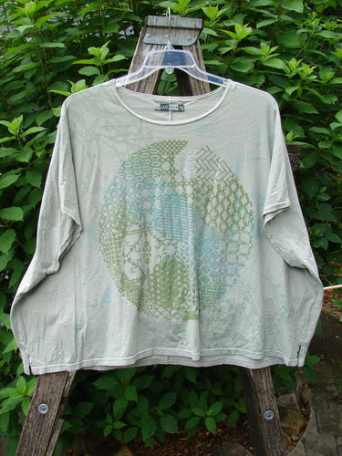 Barclay Cricket Cap Sleeve Tee Centered Dune Grass OSFA displayed outdoors on a hanger, showcasing its seamless shoulder sleeves, slight hip flare, and rounded hemline in a square boxy shape.