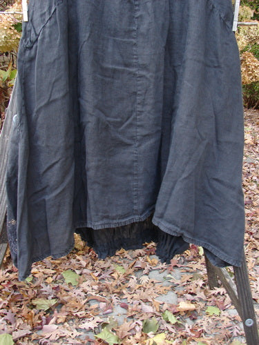 Barclay Linen Open Front Drawcord Hem Jumper in Black displayed on a rack, showcasing its layered crossover front, batiste under skirt, and elastic gathered hemline.