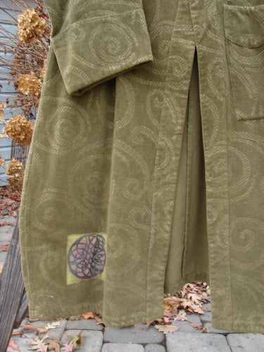 2000 Patched Upholstery Diwmach Coat in Pine, Size 2. Luxurious heavy-weight cotton with a damask swirl pattern. Scalloped neckline with vintage buttons, belled and paneled lower sleeves. A-line shape with pleated and tabbed rear. Bust 54, waist 54, hips 62. Length: 50 inches in front, graduated in the back. Sleeves cuffed and belled.