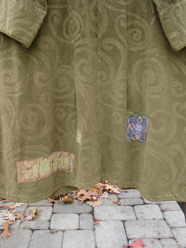 2000 Patched Upholstery Diwmach Coat in Pine, a close-up of a stunning heavy-weight tapestry cotton coat with a damask swirl pattern. Features include colorful patches, a scalloped neckline with vintage buttons, belled and paneled lower sleeves, and an A-line shape. Draping sophisticated fabric creates folds and texture. Bust 54, Waist 54, Hips 62. Length in front is 50 inches, back has a graduation. Sleeves are cuffed and belled, measuring 28 inches around.