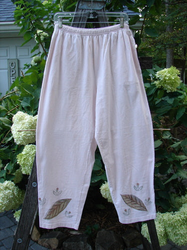 1999 Simple Vent Pant Fallen Leaf Orchid Size 1, featuring a fallen leaf theme painted on organic mid-weight cotton, displayed draped over a fence with visible elastic waistline and ankle vents.