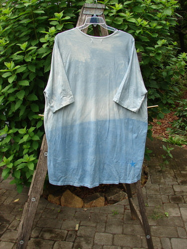 Barclay Tournesol Tunic Flower Power Mottled Day Sky OSFA displayed outdoors, showcasing its loose three-quarter sleeves, rounded neckline, and varying hemline, embodying the creative freedom of Blue Fish Clothing.