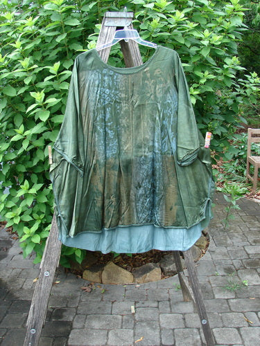 Barclay Viscose Vitreous High Low Tunic Botanicals Mottled Forest Sun OSFA, showcasing a distinctive rounded neckline, three-quarter dolman sleeves, and a varying hem with exterior stitchery and botanical motifs.