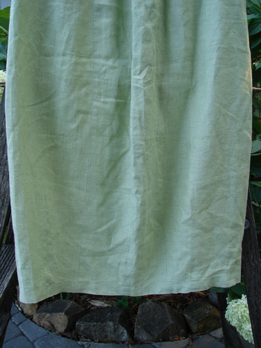 2000 Cross Dye Linen Contour Skirt Unpainted Celery Size 0 hanging outdoors, showcasing its full elastic waistband, vertically paneled sides, and reverse bell bottom accents for a contoured lower shape.