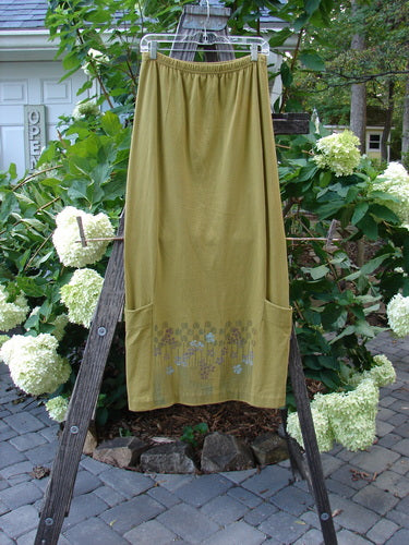 2000 Leaflet Skirt Garden Peapod Altered Size 0 displayed hanging on a wooden ladder, showcasing its dynamic tapered hemline, billowy wrap-around pockets, and detailed colorful garden theme paint.