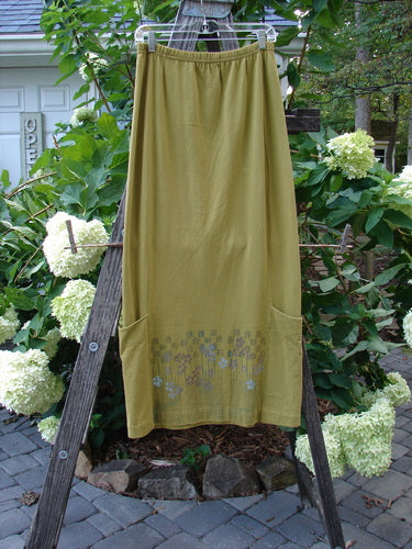 2000 Leaflet Skirt Garden Peapod Altered Size 0, displayed on a wooden ladder, featuring a slightly tapered hemline, billowy wrap-around pockets, and colorful garden-themed paint.