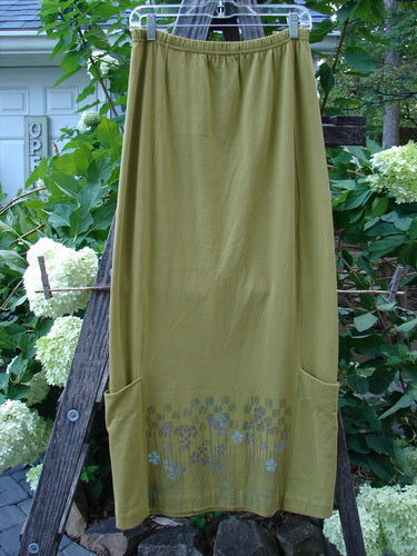 2000 Leaflet Skirt Garden Peapod Altered Size 0, displayed on a wooden ladder, showcasing a dynamic tapered hemline, billowy wrap-around lower drop pockets, and garden-themed paint details.