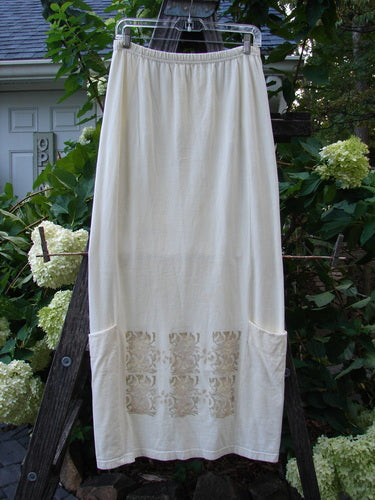 2000 Leaflet Skirt Garden Gates Milk Size 1 hanging on a clothesline, showcasing its dynamic hemline, wrap-around pockets, and colorful garden gate pattern on organic cotton fabric.