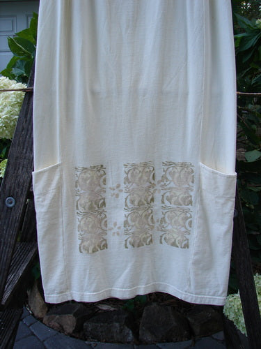 2000 Leaflet Skirt Garden Gates Milk Size 1: A white organic cotton skirt featuring a dynamic tapered hemline, wrap-around lower drop pockets, full elastic waistband, and colorful garden gate theme design.