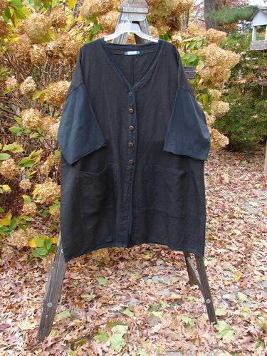 Barclay Cotton Sleeve Pocket Cardigan Unpainted Black Size 2 displayed on a hanger, featuring wooden-like buttons, upward curved hemlines, drop shoulders, curly sleeves, and front squared pockets.